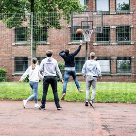 Vier Berufsschüler:innen spielen Basketball im Innenhof