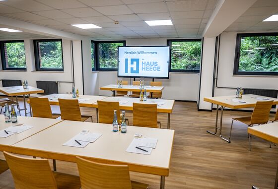 Seminarraum mit Tischen, Stühlen, Getränken und einem Präsentationsbildschirm