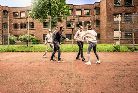 Vier Personen spielen Basketball im Innenhof