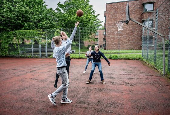 Vier Personen spielen Basketball im Innenhof