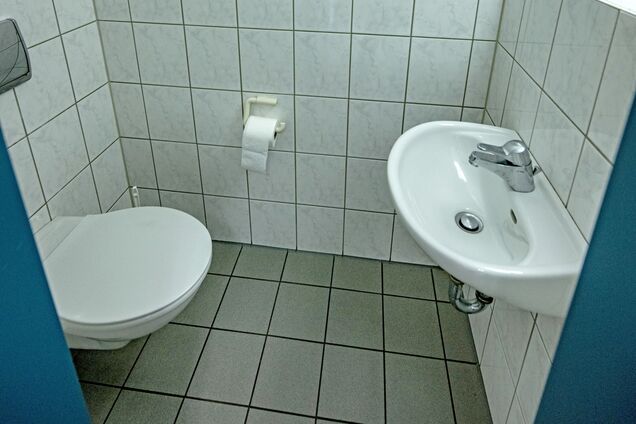 Weiß gefliestes Badezimmer mit Toilette und Waschbecken