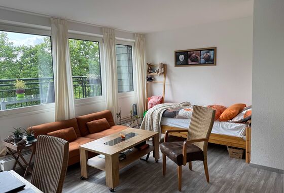 Einliegerwohnung mit Schreibtisch, Sofa, Bett und Balkon