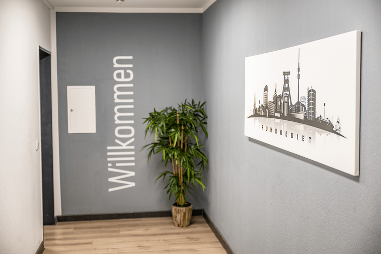 Flur zur Rezeption mit Bildern und Willkommens-Schriftzug auf der Wand