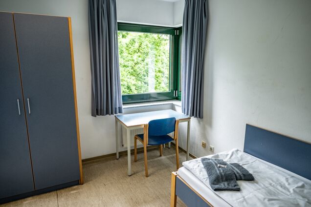 Einzelbett, Kleiderschrank und Schreibtisch mit Fenster ins Grüne