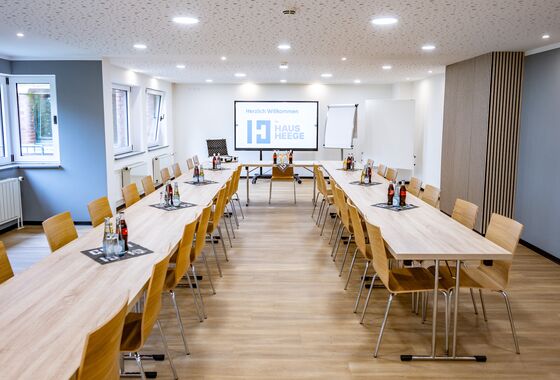 Tische und Stühle in einem Seminarraum mit Präsentationsbildschirm
